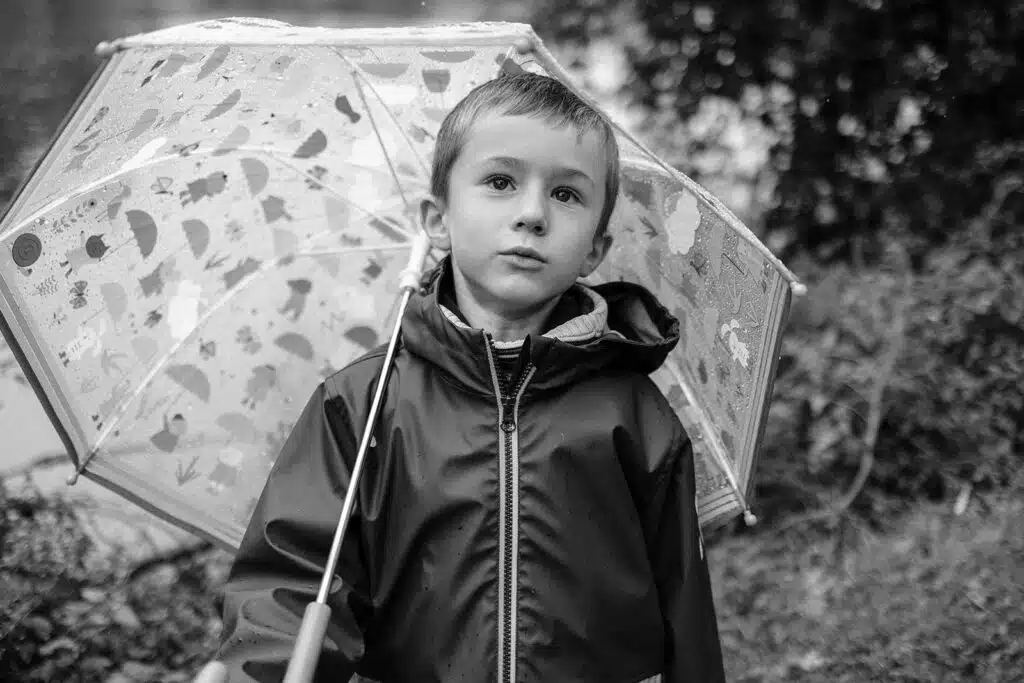 Garçon sérieux avec parapluie transparent en noir et blanc