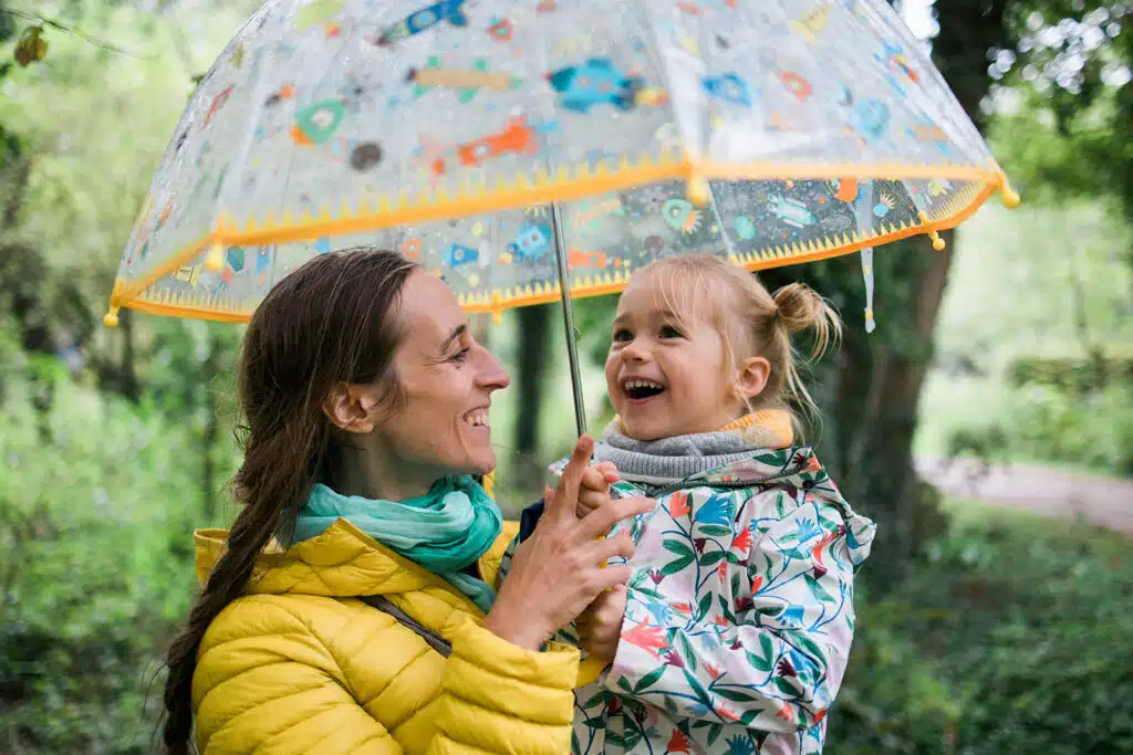 Mère et fille souriant sous un parapluie coloré