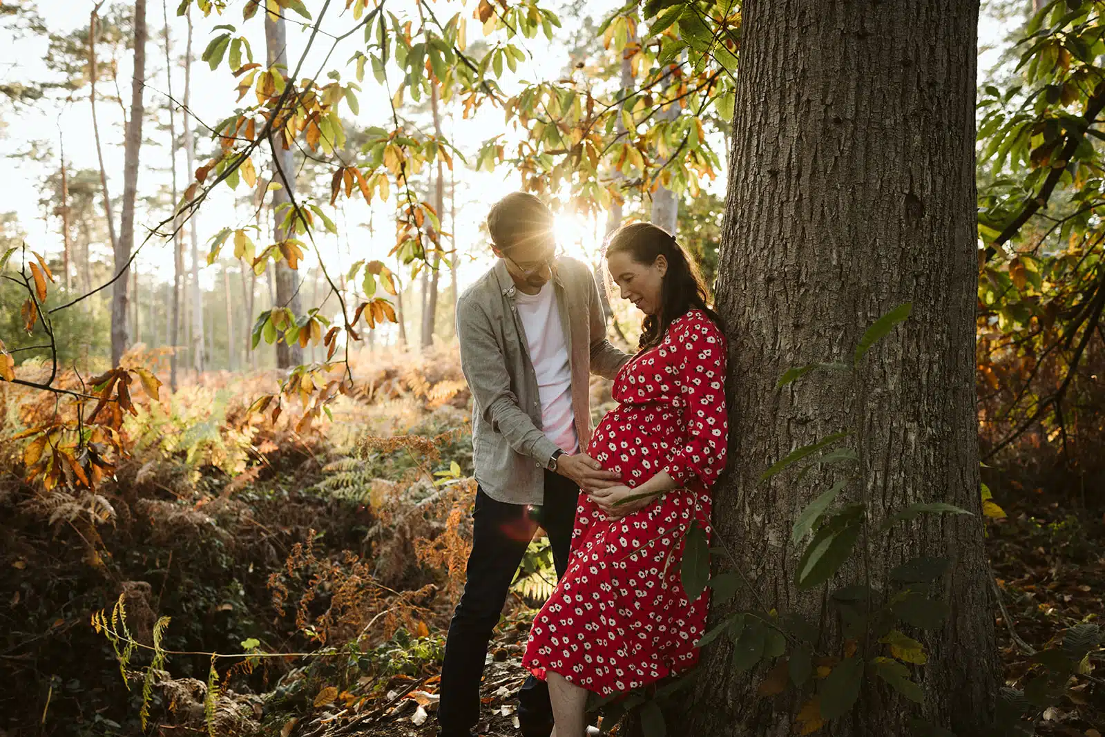 Femme enceinte en robe rouge avec son conjoint en foret de Marchiennes