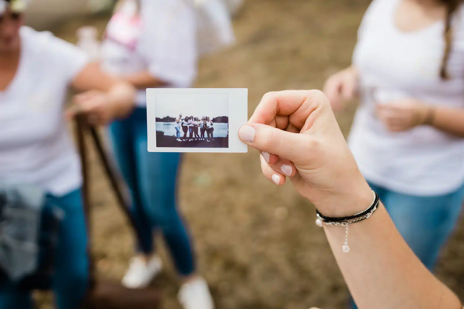 Main qui tient le polaroïd du groupe pendant la séance EVJF