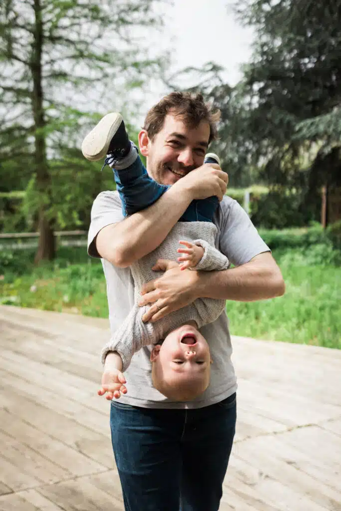 Père jouant avec son enfant en plein air.