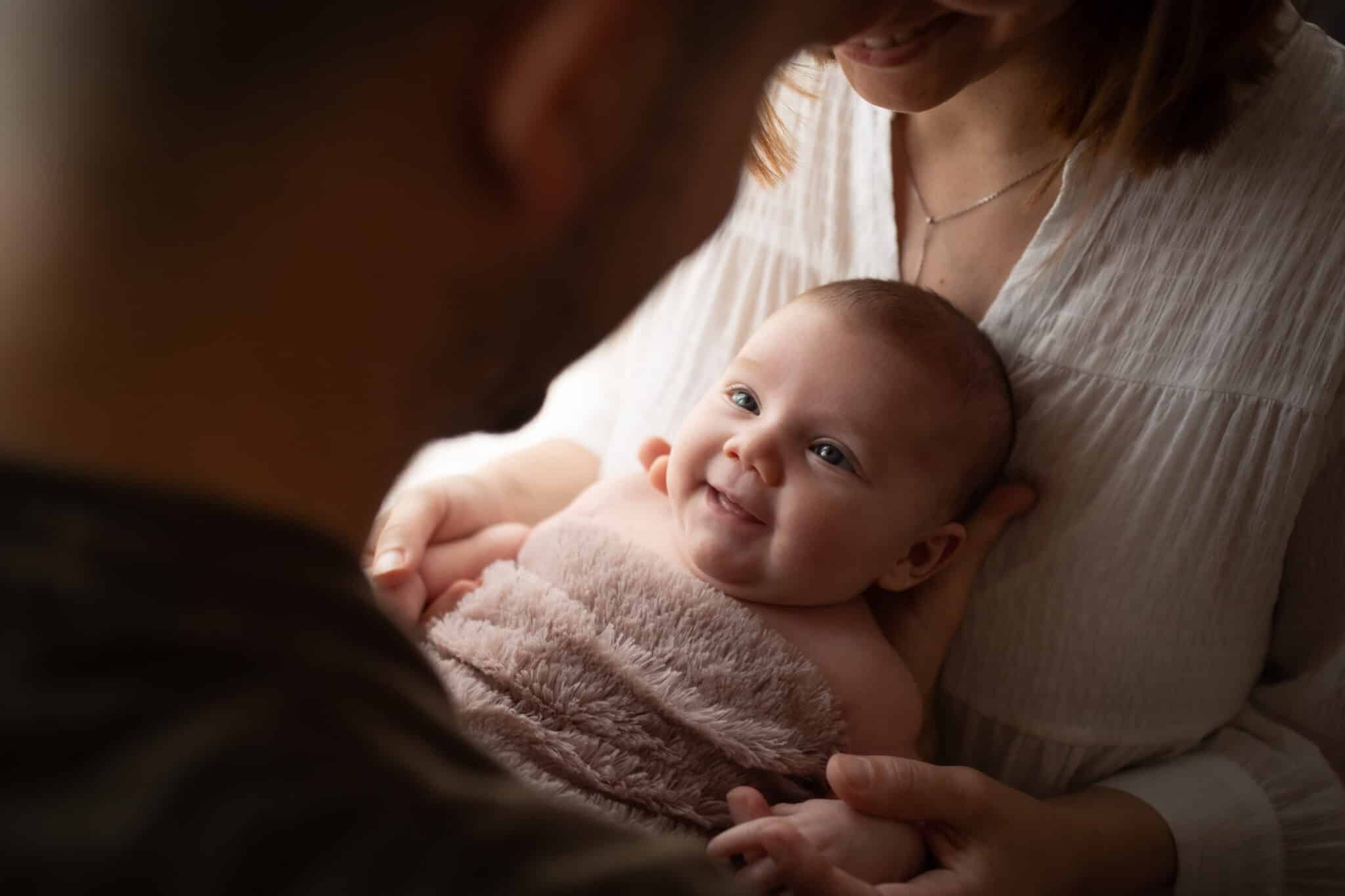 Bébé souriant avec parents, moment familial tendre.