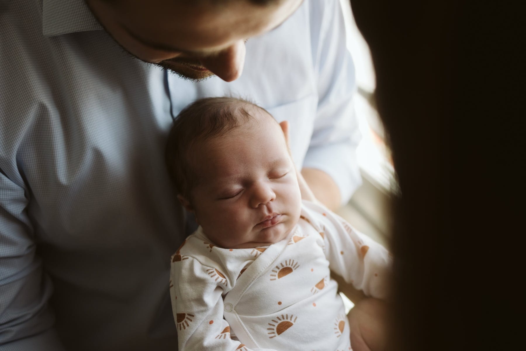 Homme tenant bébé endormi doucement.