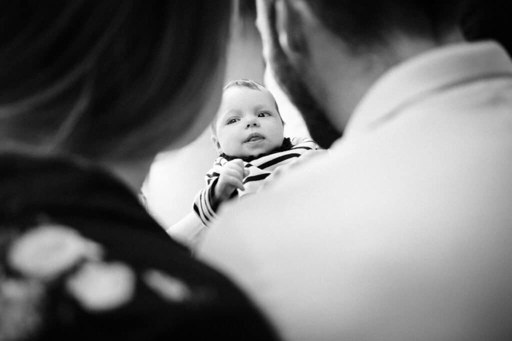 Bébé souriant entre parents en noir et blanc