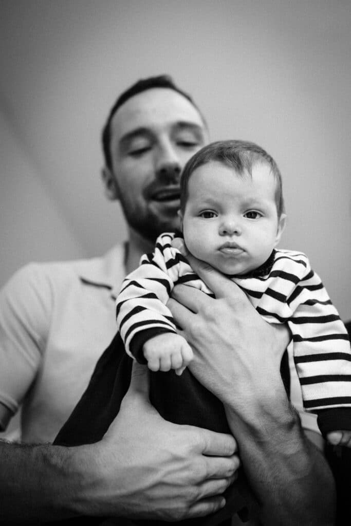 Père tenant bébé en noir et blanc.