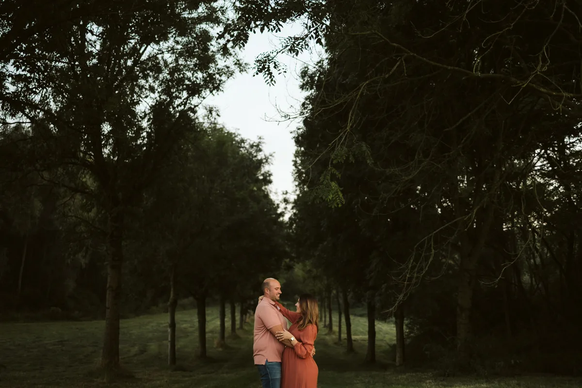 Futurs parents enlaces dans une allee arboree au crepuscule