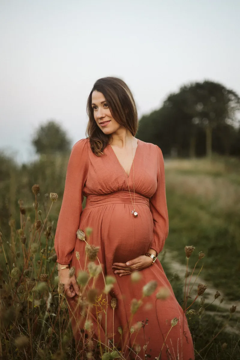 Femme enceinte en robe dans les herbes hautes pres de Lille