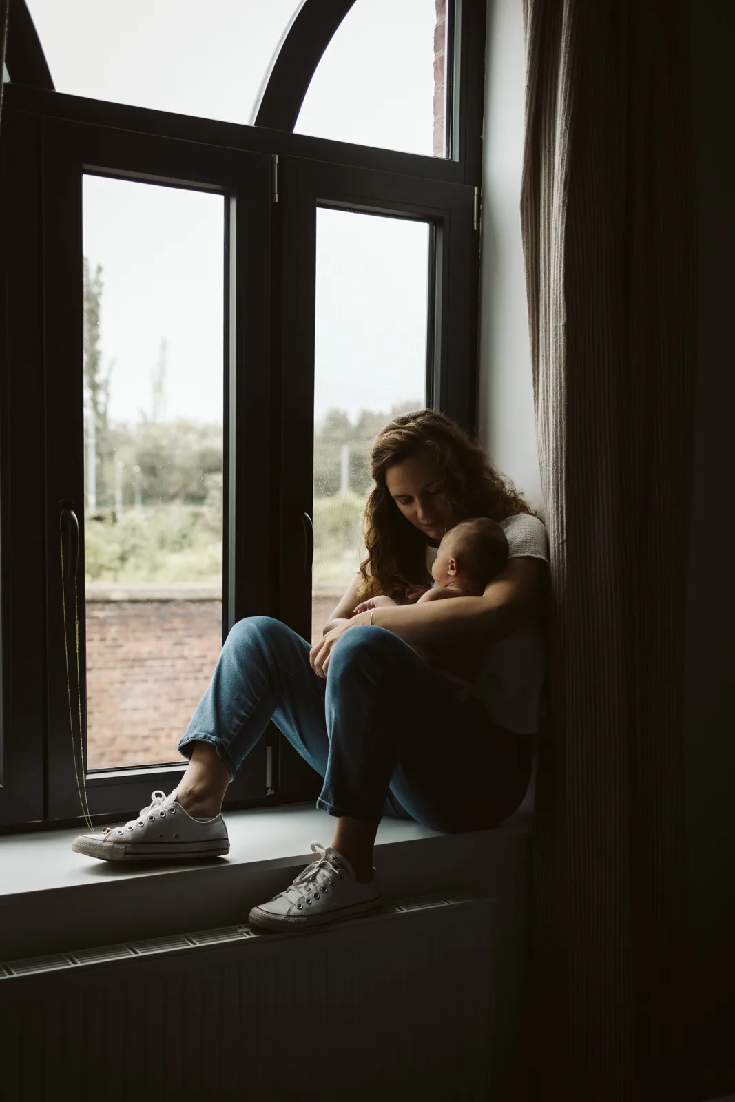 Mère câlinant bébé près fenêtre.