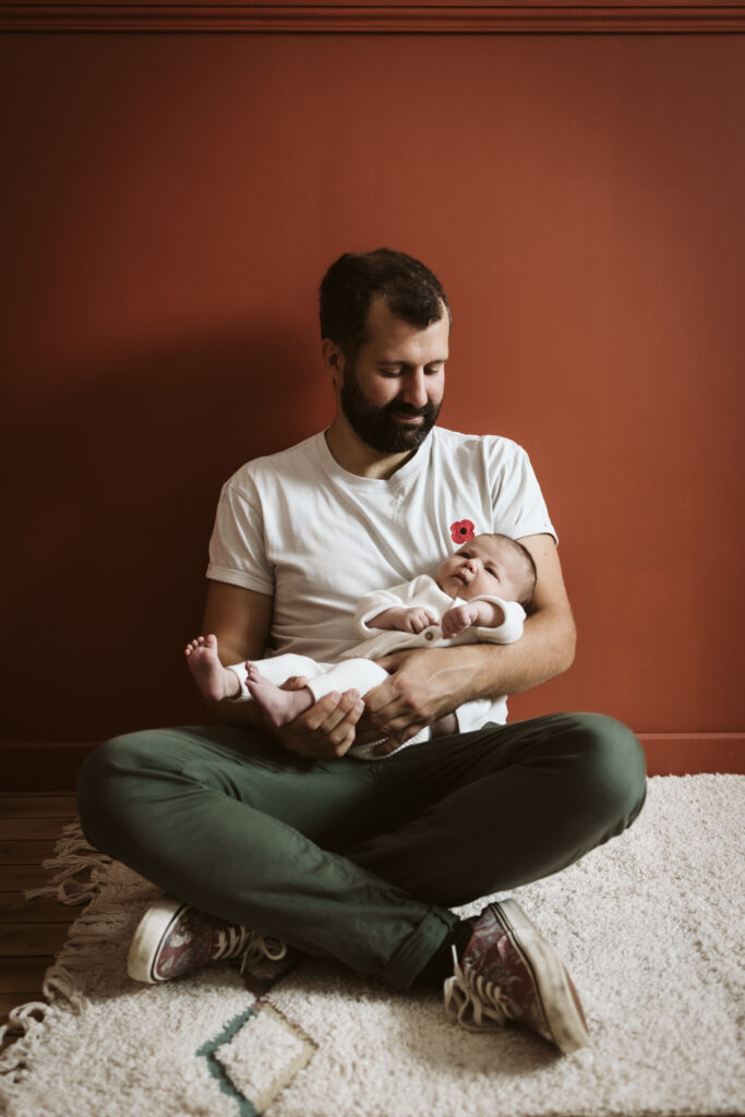Homme souriant tenant bébé endormi.