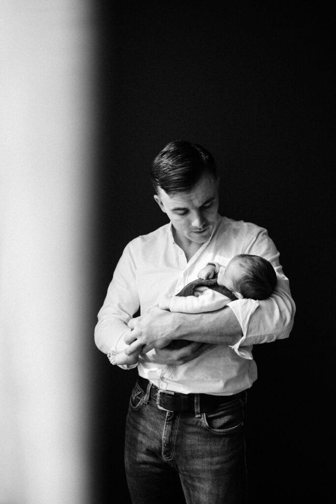 Homme tenant doucement un bébé.