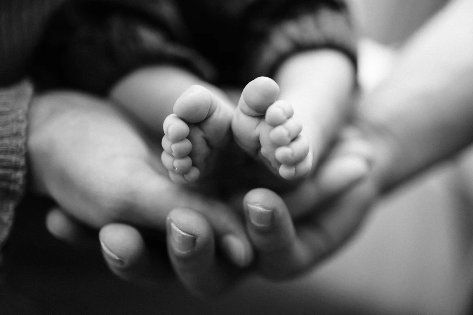 Gros plan sur les pieds du nouveau-ne dans les mains de ses parents