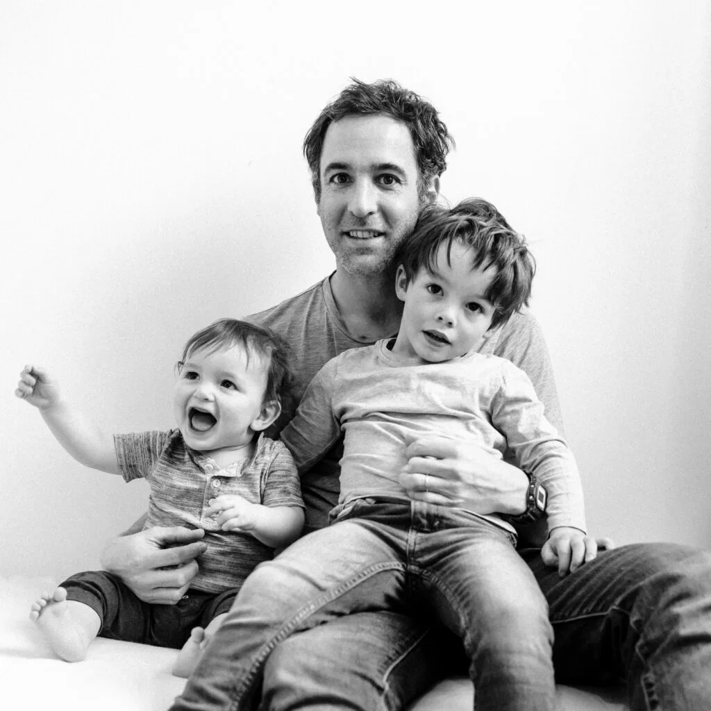 Père souriant avec deux jeunes enfants joyeux.