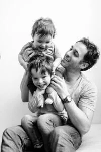 Père souriant avec deux enfants heureux en noir et blanc.