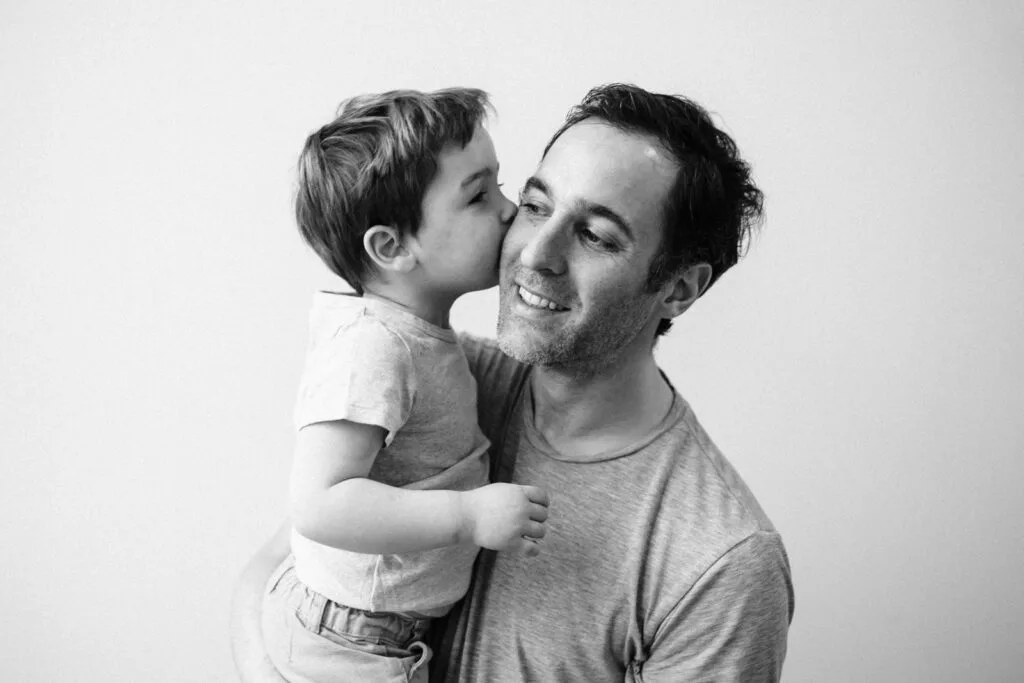 Enfant embrassant son père, photo en noir et blanc.