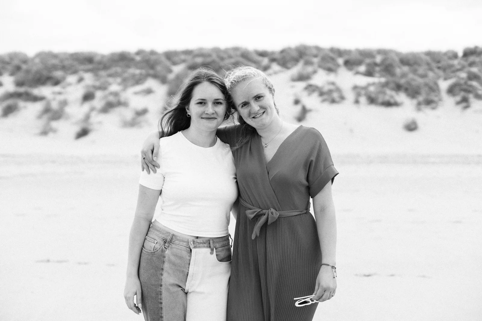 Deux femmes souriantes sur une plage sableuse