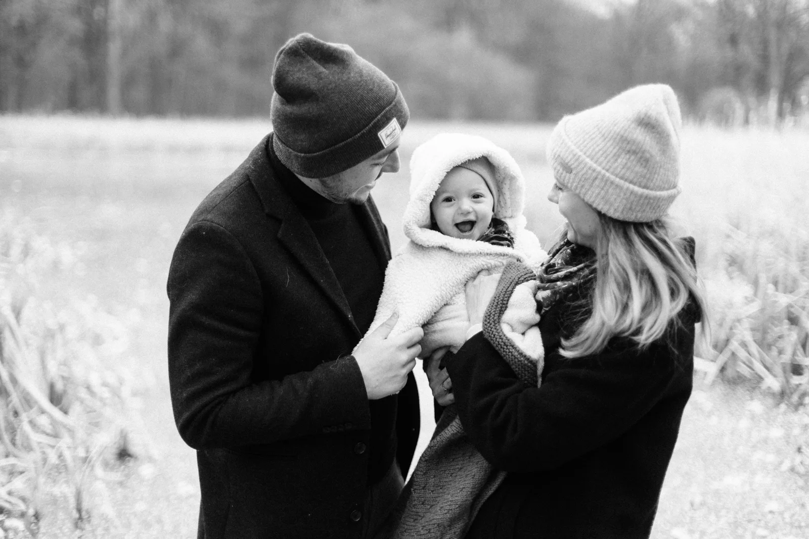 Papa et maman faisant un calin a leur bebe en noir et blanc