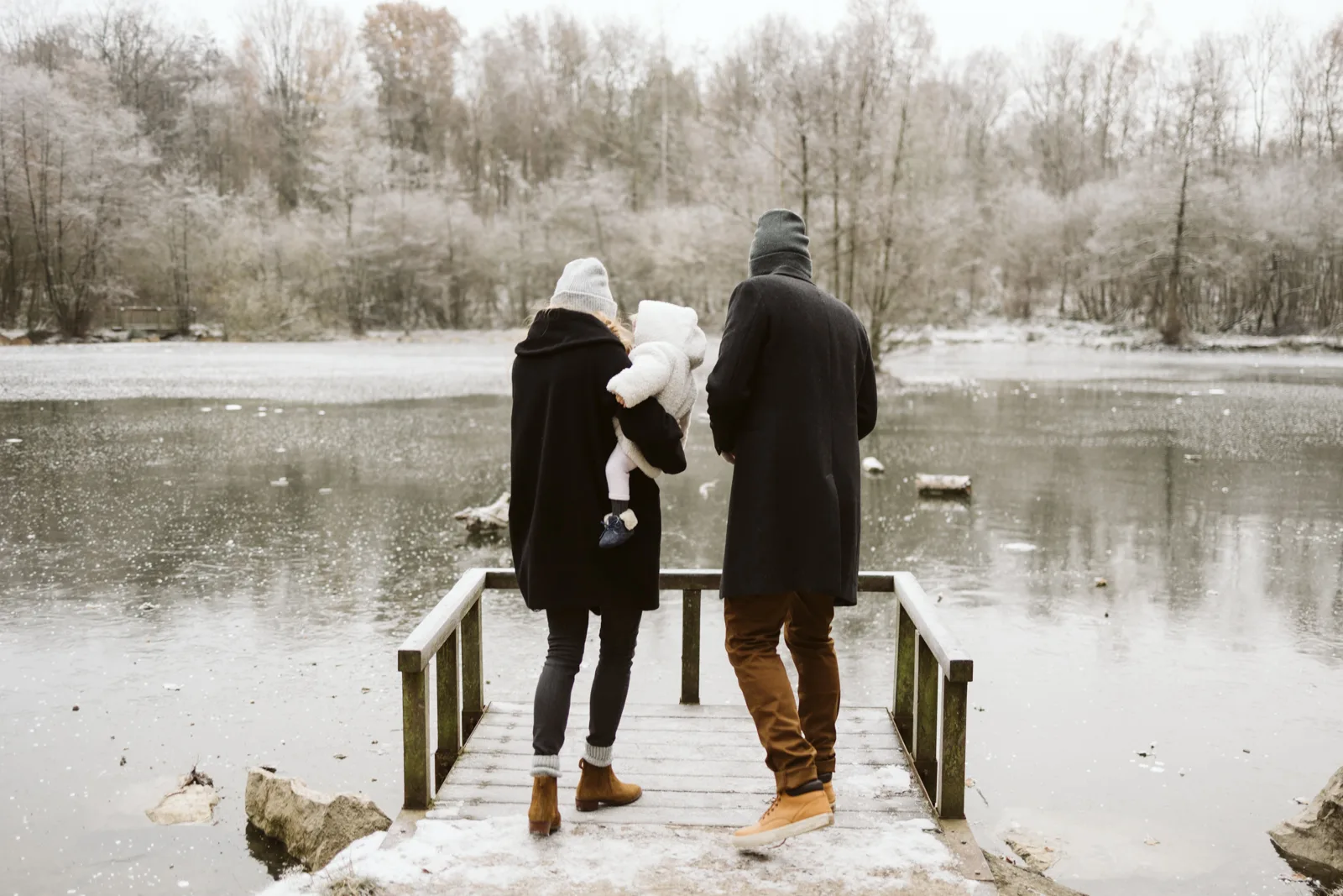 Famille avec bebe sur un ponton au bord du lac en hiver
