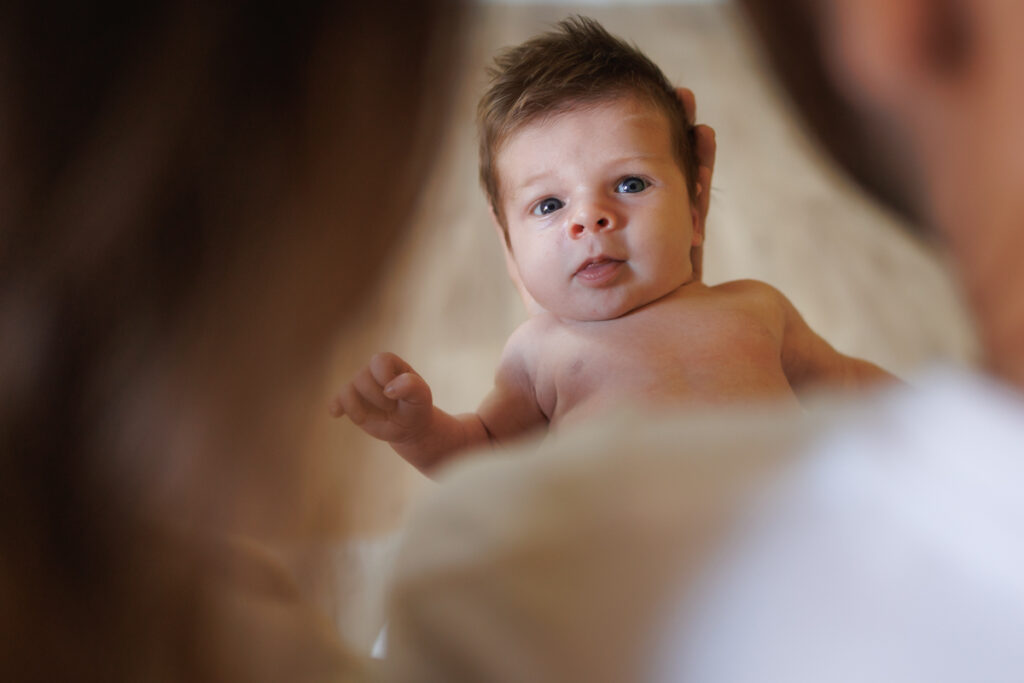 Parents avec leur bébé dans les bras pendant une séance photo naissance