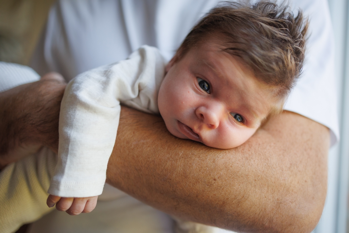Papa tenant bebe allongé sur son bras pendant une seance photo naissance pres de douai