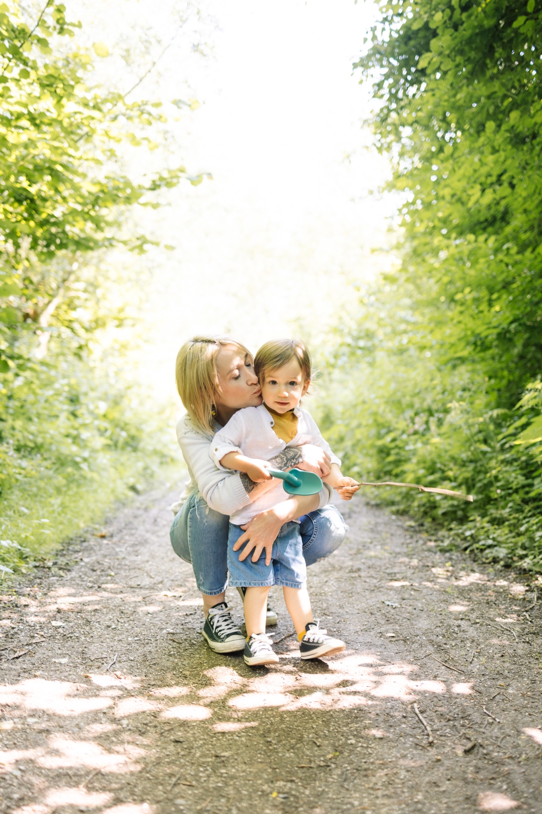 Maman embrassant son enfant sur un chemin boisé - photographe famille Arras