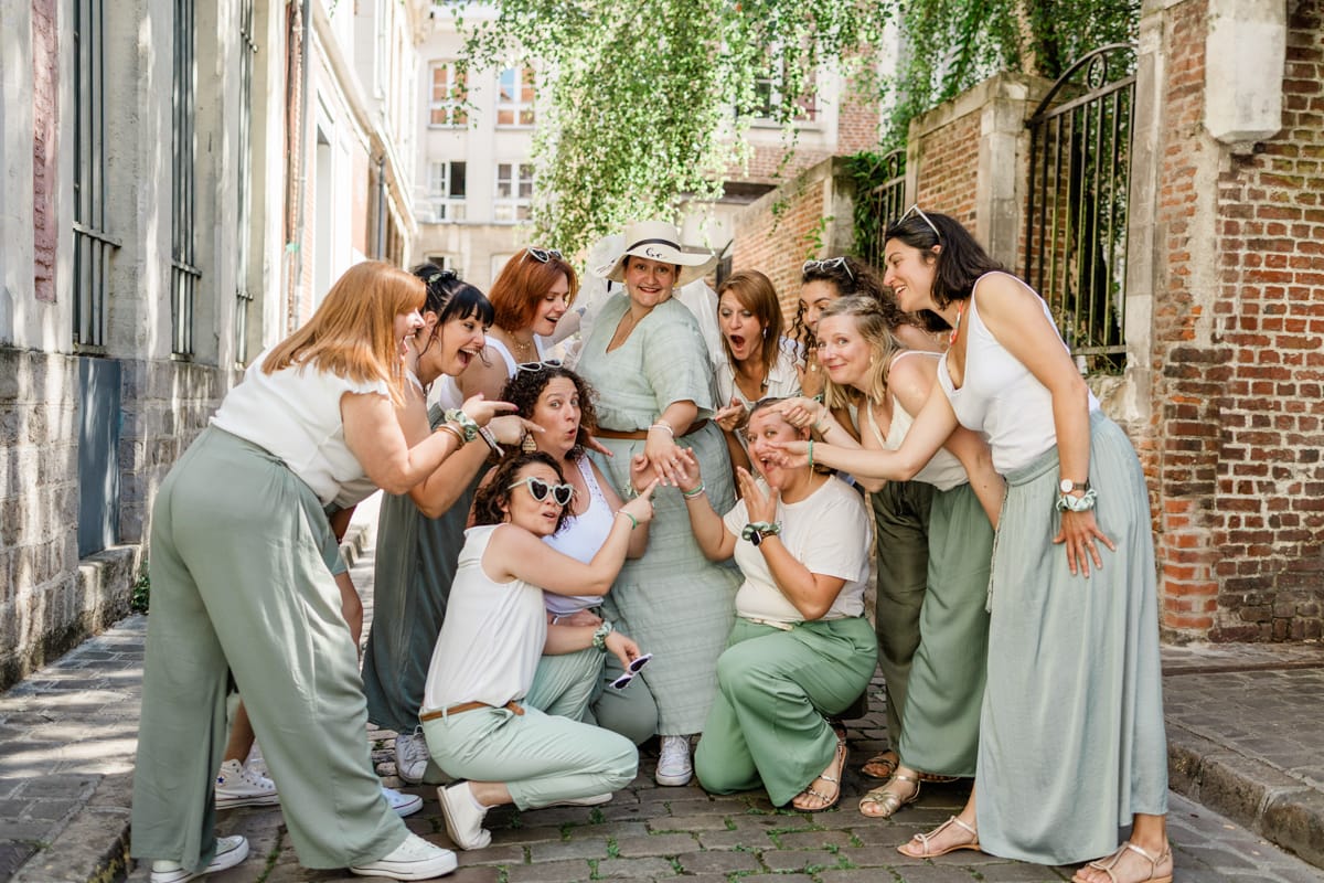 Groupe d amies en tenue vert sauge et blanc fetant un EVJF dans les rues pavees du Vieux Lille