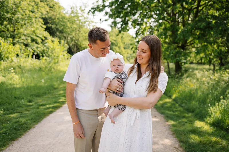 Papa et maman portant leur bebe sur un chemin du parc du Heron