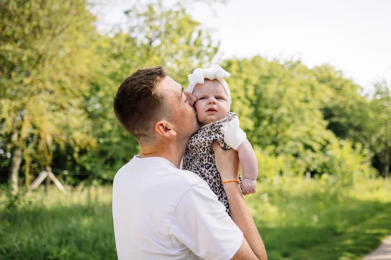 Papa embrassant sa fille sur la joue pendant une seance photo famille