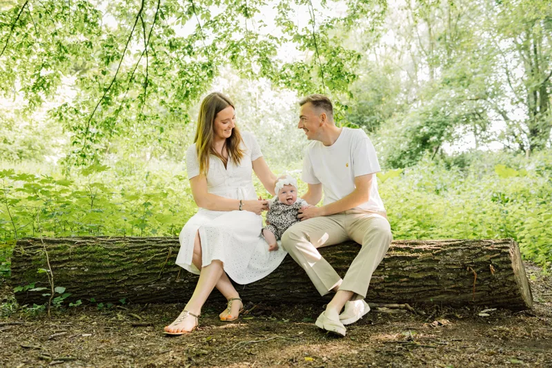 Parents assis sur un tronc avec leur bebe au parc du Heron