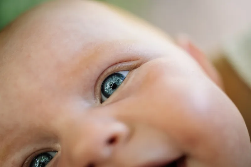 Gros plan sur le visage souriant du bebe aux yeux bleus