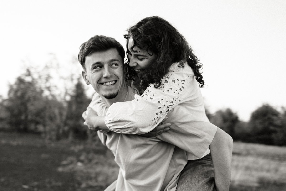 Valentin porte Sarah sur son dos, éclat de rire en noir et blanc